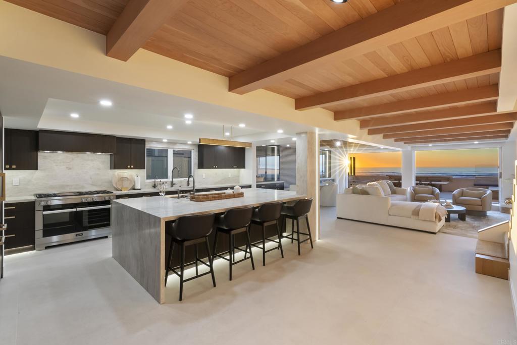 a large kitchen with stainless steel appliances granite countertop a stove and a view of living room