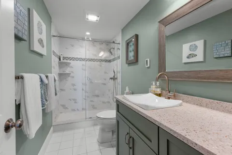 a bathroom with a granite countertop sink a toilet and shower