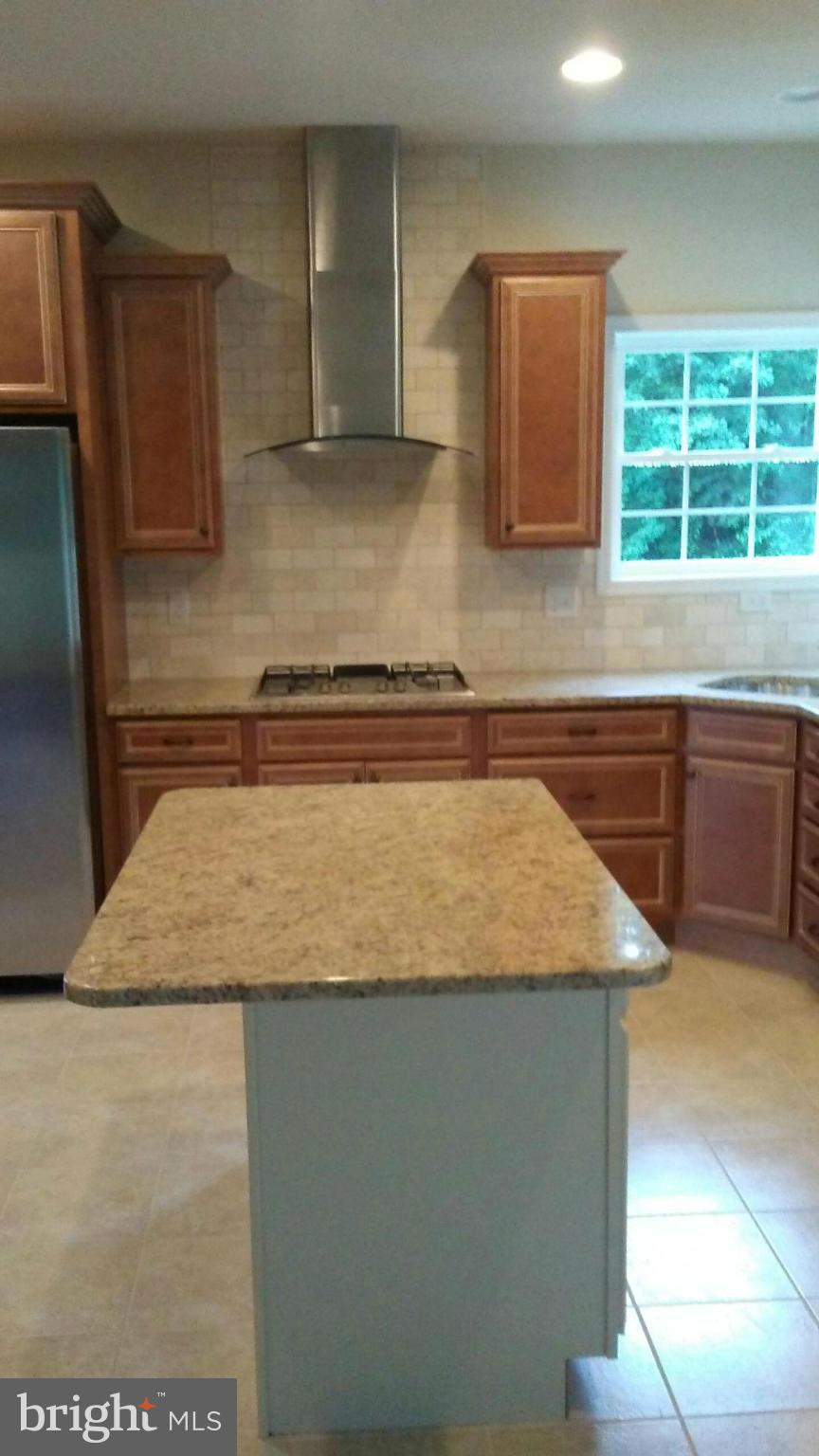 17523 Falls Road Upperco, MD 21155 - Photo 18 of 19 a kitchen with granite countertop sink a stove a microwave and wooden cabinets