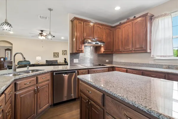a kitchen with stainless steel appliances granite countertop a sink a stove and cabinets