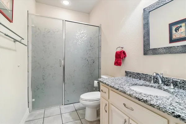 a bathroom with a granite countertop sink a toilet and shower