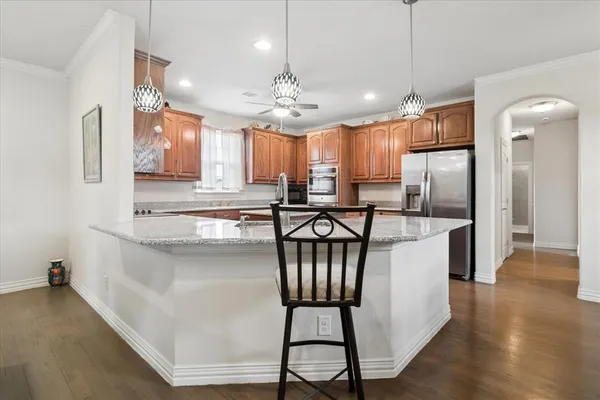 a kitchen with stainless steel appliances granite countertop a refrigerator a stove a sink dishwasher a dining table and chairs with wooden floor