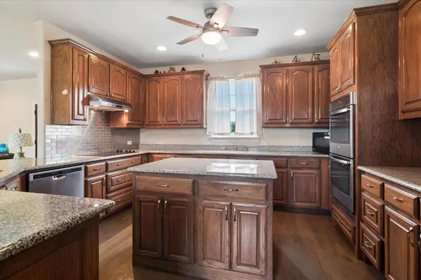 a kitchen with kitchen island granite countertop a sink stainless steel appliances and cabinets