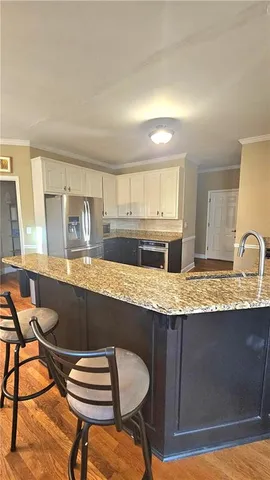 a kitchen with kitchen island granite countertop a table chairs sink and cabinets