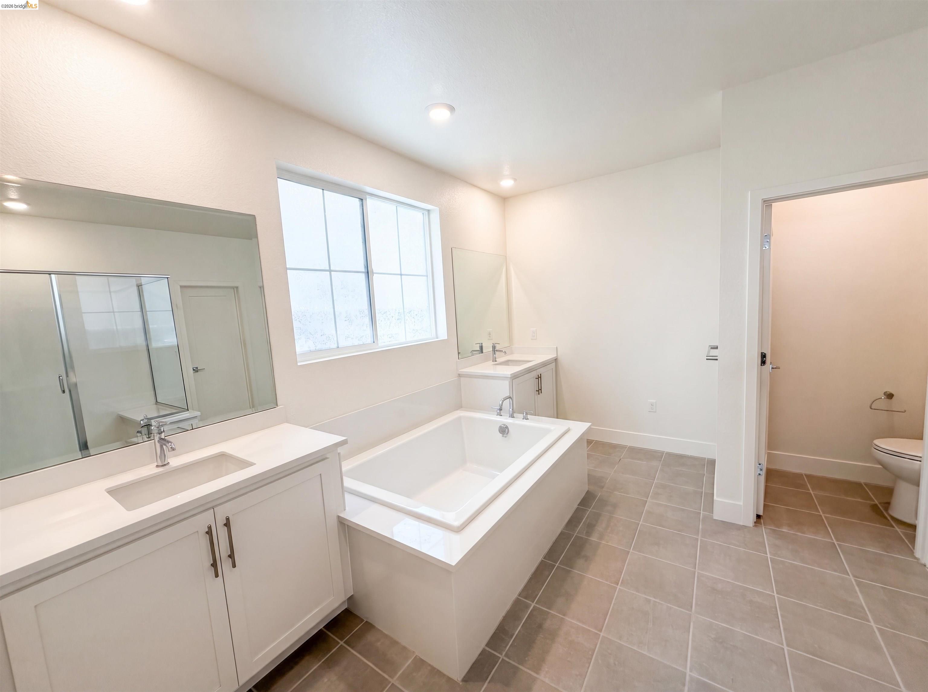 9034 Rudder Way Newark, CA 94560 - Photo 8 of 38 Spacious bathroom with dual vanities, white cabinetry, integrated sinks, a built-in bathtub, and tiled flooring