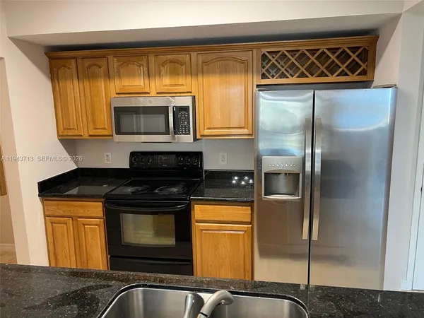 a kitchen with granite countertop a refrigerator and a stove top oven