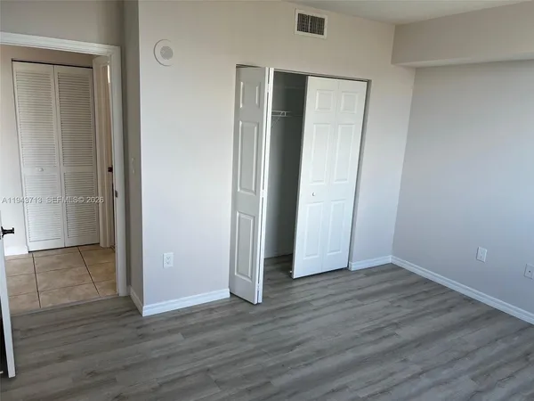 an empty room with wooden floor & closet area