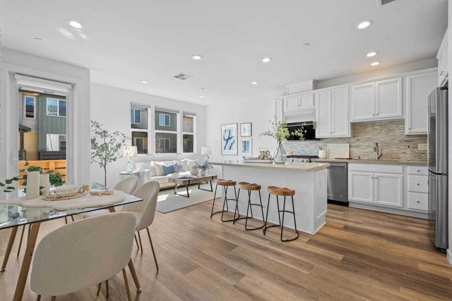 a large white kitchen with sink a stove a dining table and chairs