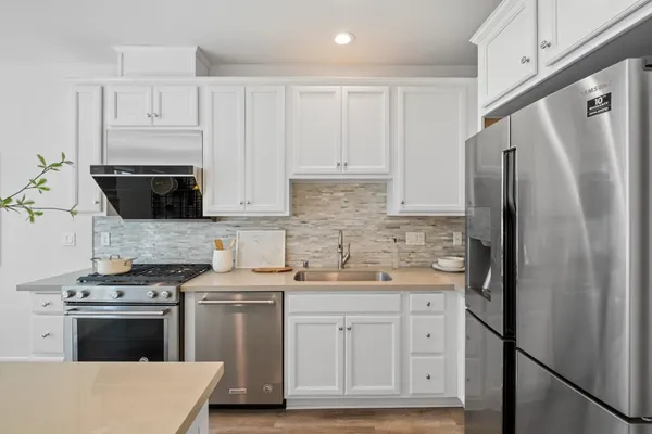 a kitchen with stainless steel appliances white cabinets and a refrigerator