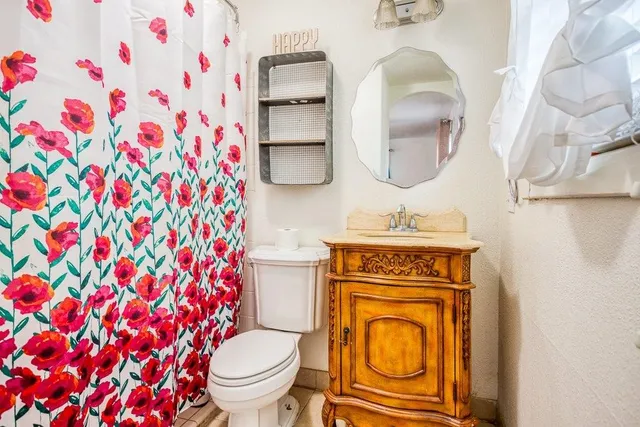 a bathroom with a granite countertop toilet a sink and a mirror