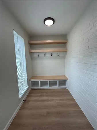 a view of an empty room with wooden floor and window