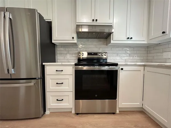 a kitchen with stainless steel appliances white cabinets and a refrigerator