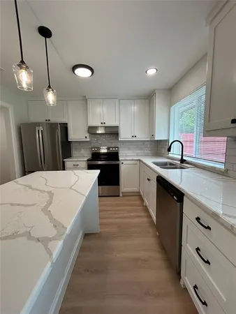 a large kitchen with stainless steel appliances granite countertop a sink a stove and a refrigerator
