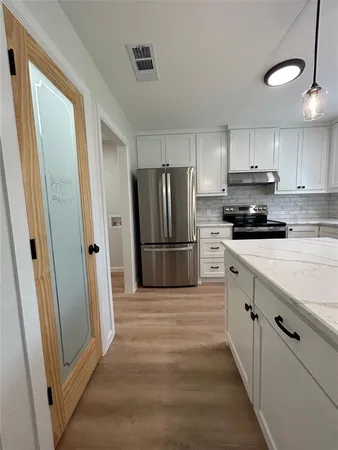 a kitchen with granite countertop a refrigerator and a stove top oven