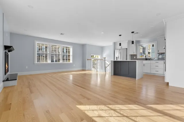 a view of a kitchen with kitchen island a sink wooden floor and living room view