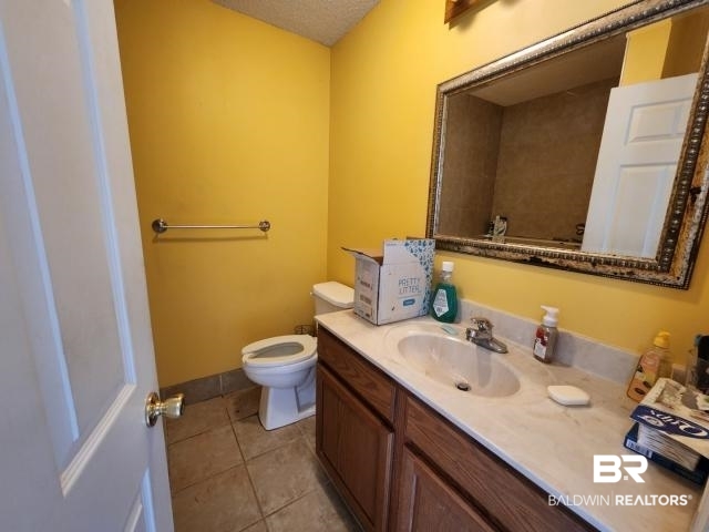 32749 Antietam Road Lillian, AL 36549 - Photo 33 of 47 Bathroom featuring vanity, toilet, tile patterned floors, and a textured ceiling