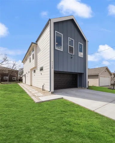 a view of a yard in front of a house with plants and large tree