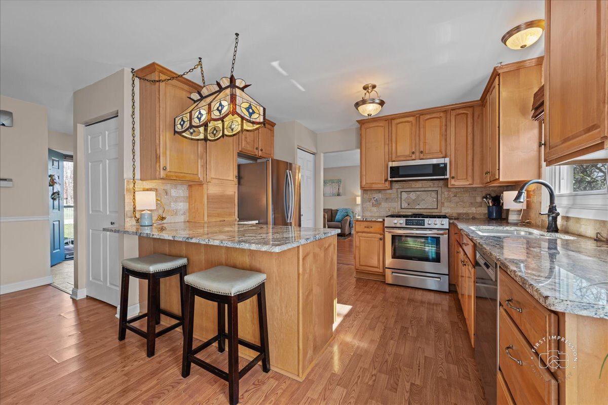 2138 Derby Court Wheaton, IL 60189 - Photo 7 of 24 a kitchen with stainless steel appliances granite countertop a refrigerator a stove top oven a sink dishwasher and wooden cabinets with wooden floor