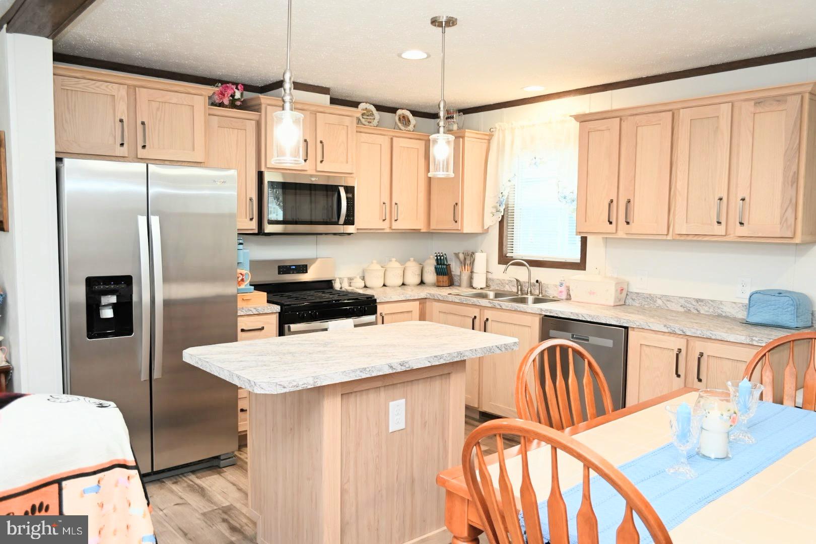 103 Carbridge Road East Stewartstown, PA 17363 - Photo 6 of 28 a kitchen with stainless steel appliances granite countertop a refrigerator a stove a sink dishwasher a dining table and chairs with wooden floor