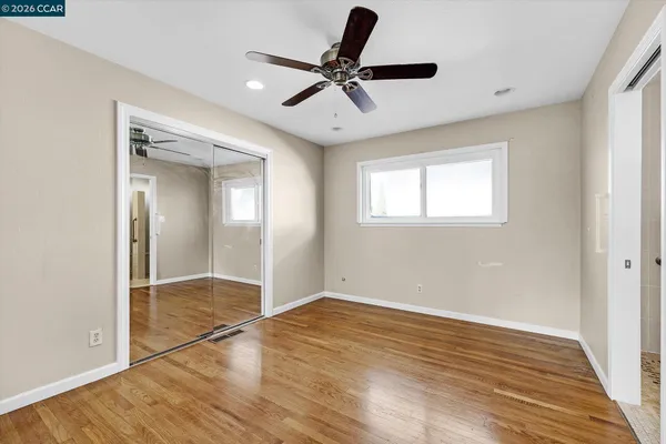 an empty room with wooden floor and ceiling fan