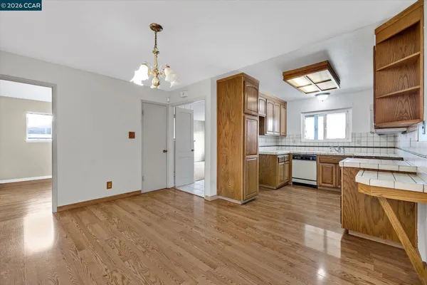 a kitchen with stainless steel appliances granite countertop a refrigerator a sink dishwasher a stove and a dining table with wooden cabinet