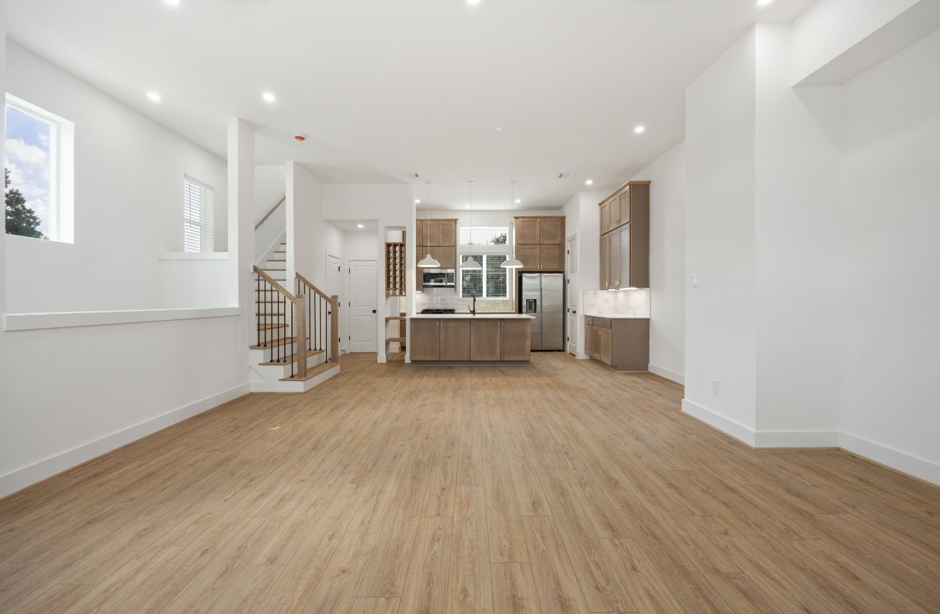 2121 Hoskins Drive, Unit C Houston, TX 77080 - Photo 14 of 34 A wide view of the main level highlights the home’s open-concept design, with living, dining, and kitchen spaces connected in one expansive setting. High ceilings, clean white walls, warm flooring, and recessed lights create a fresh, modern atmosphere ready for personal style.