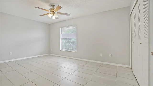 an empty room with windows and fan