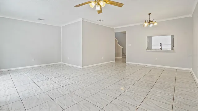 a view of an empty room and chandelier fan