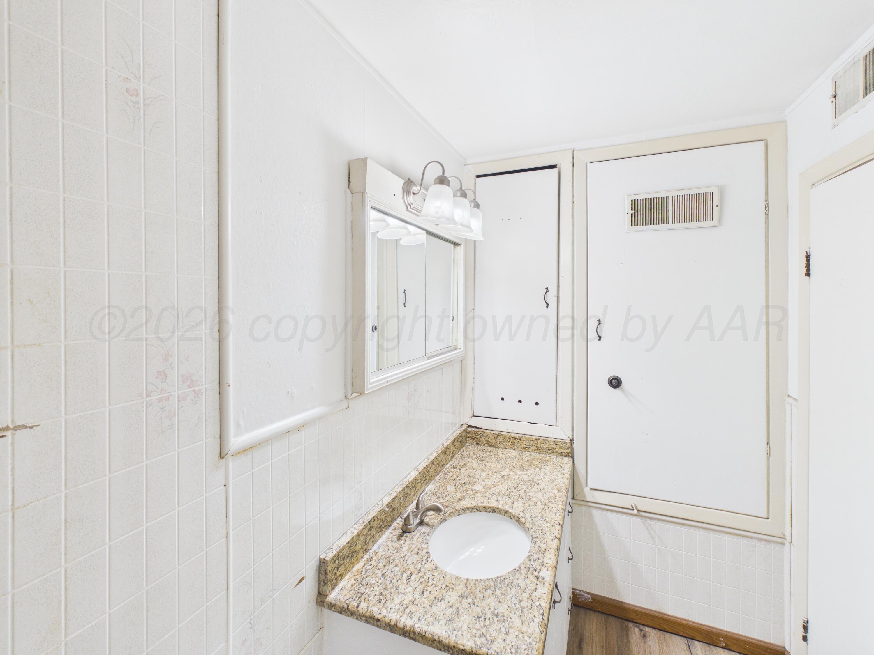 813 Northeast 3rd Street Dumas, TX 79029 - Photo 11 of 22 a bathroom with a granite countertop sink a mirror and shower