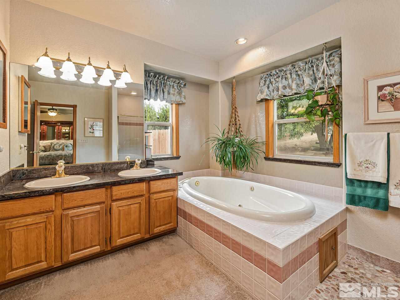 35 Calla Lily Court Reno, NV 89511 - Photo 17 of 39 a spacious bathroom with a double vanity sink a large mirror and a bathtub