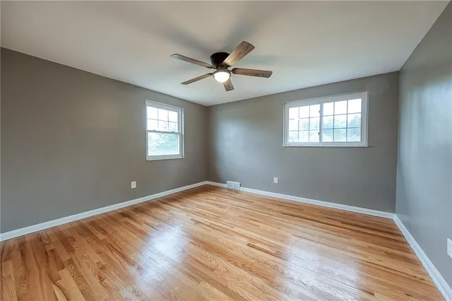 a view of an empty room with window and wooden floor