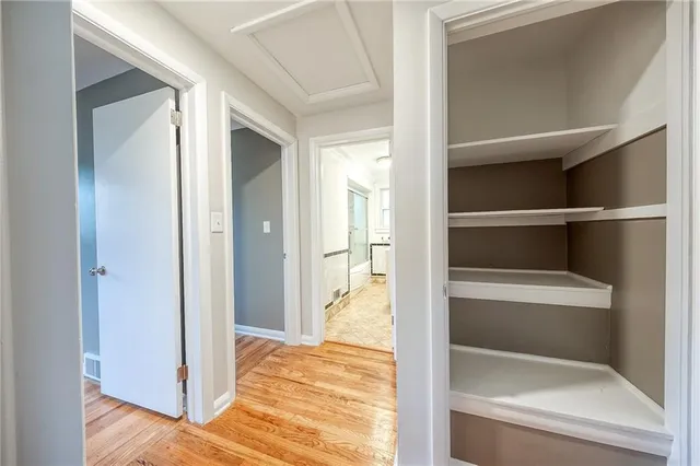 a view of a hallway with wooden floor and a bathroom