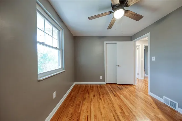 a view of empty room with wooden floor and fan