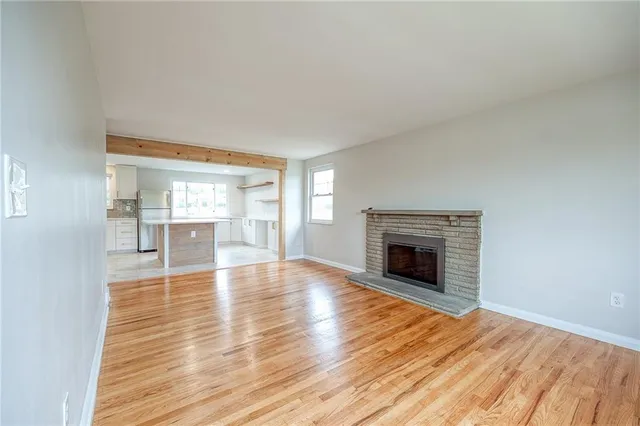an empty room with wooden floor fireplace and windows