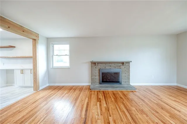 a view of empty room with wooden floor and fireplace