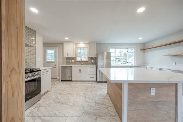 a kitchen with stainless steel appliances granite countertop a stove a sink and a refrigerator