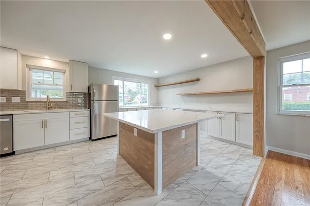 a kitchen with stainless steel appliances kitchen island granite countertop a stove a sink and a refrigerator