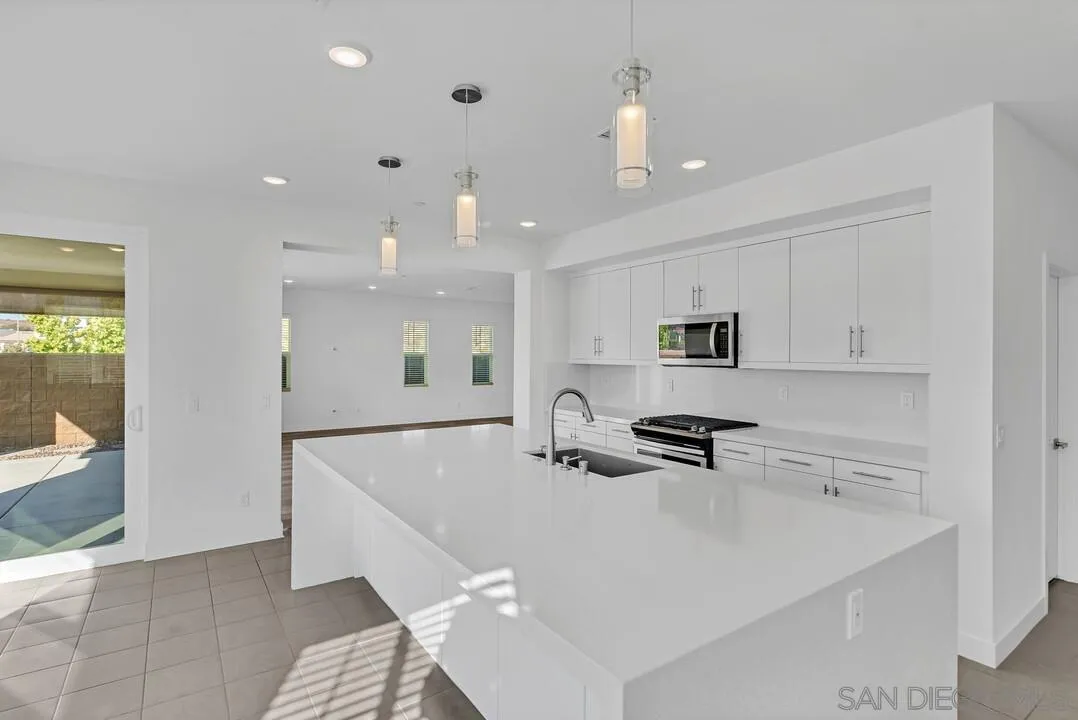 9041 West Bluff Place Santee, CA 92071 - Photo 7 of 42 a kitchen with kitchen island a sink a stove and a refrigerator with wooden floor