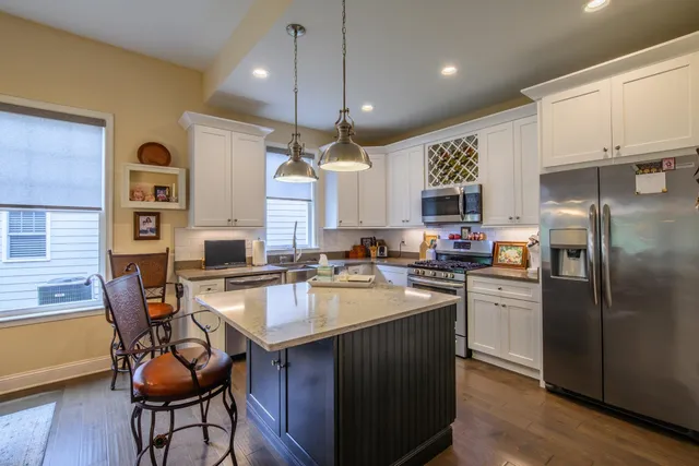 a kitchen with stainless steel appliances granite countertop a refrigerator a sink dishwasher a stove and a refrigerator