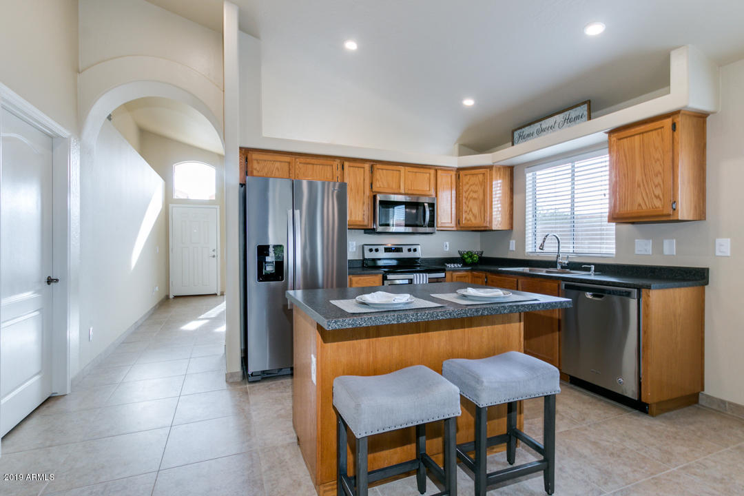 7292 South Roberts Road Tempe, AZ 85283 - Photo 4 of 38 a kitchen with stainless steel appliances granite countertop a stove a sink a refrigerator a microwave a dining table and chairs