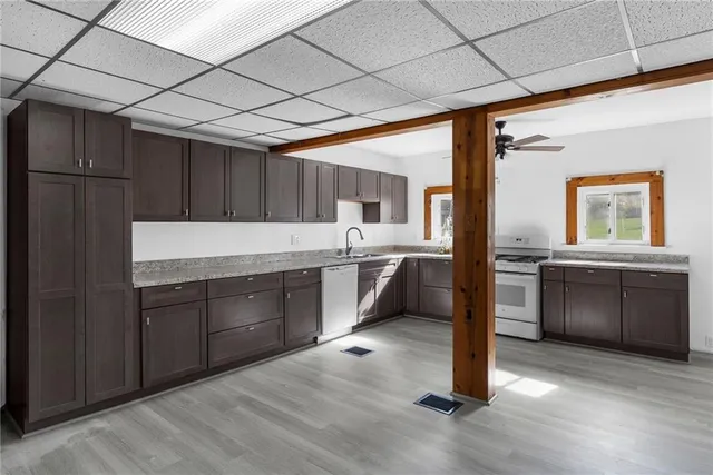 a kitchen with stainless steel appliances granite countertop a refrigerator a sink dishwasher a stove with wooden cabinets and floors