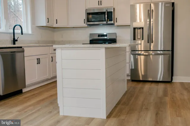 a kitchen with cabinets stainless steel appliances and wooden floor