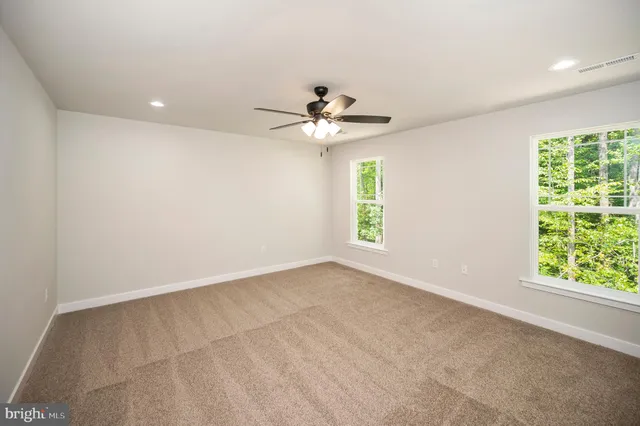 an empty room with windows and chandelier fan