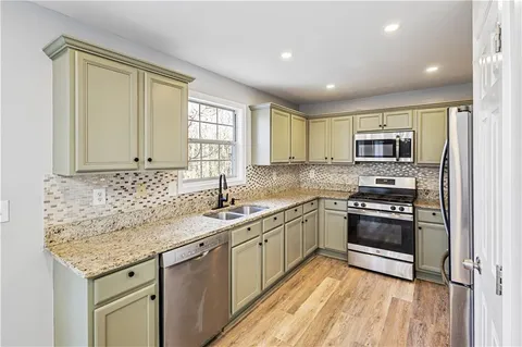 a kitchen with stainless steel appliances granite countertop a refrigerator and a sink