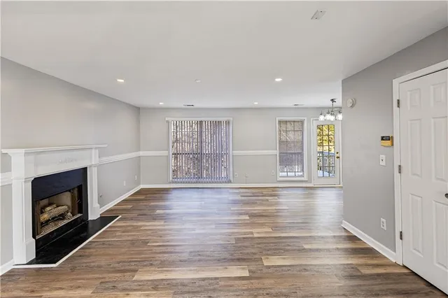 a view of an empty room with wooden floor and a fireplace