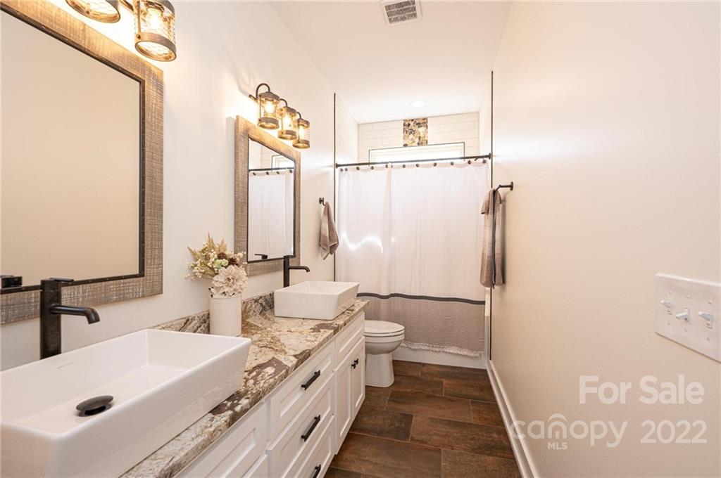 1289 Hopewell Church Road Hiddenite, NC 28636 - Photo 35 of 48 a bathroom with a double vanity sink a mirror and a bathtub