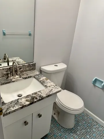 a bathroom with a granite countertop toilet and a sink