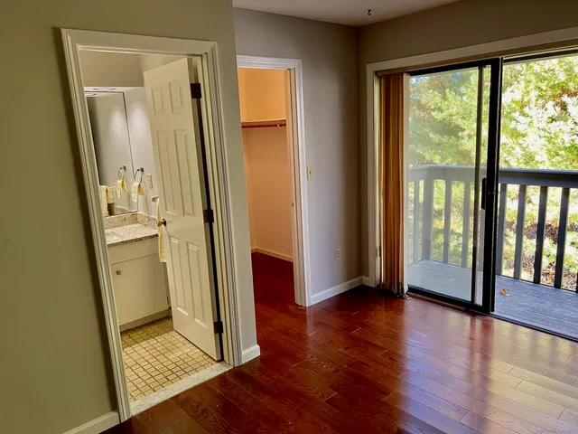 a view of a hallway with wooden floor and a bathroom