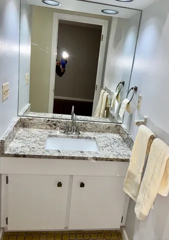 a bathroom with a granite countertop sink and a mirror