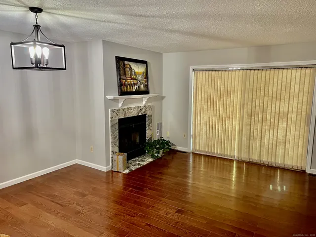 a view of a livingroom with wooden floor and a fireplace